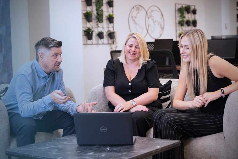 Three colleagues going through a booking on a laptop